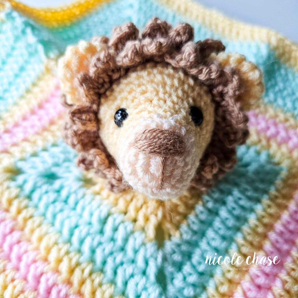Proper placement of the crochet lion head onto the blanket for the lion lovey pattern, view 2.