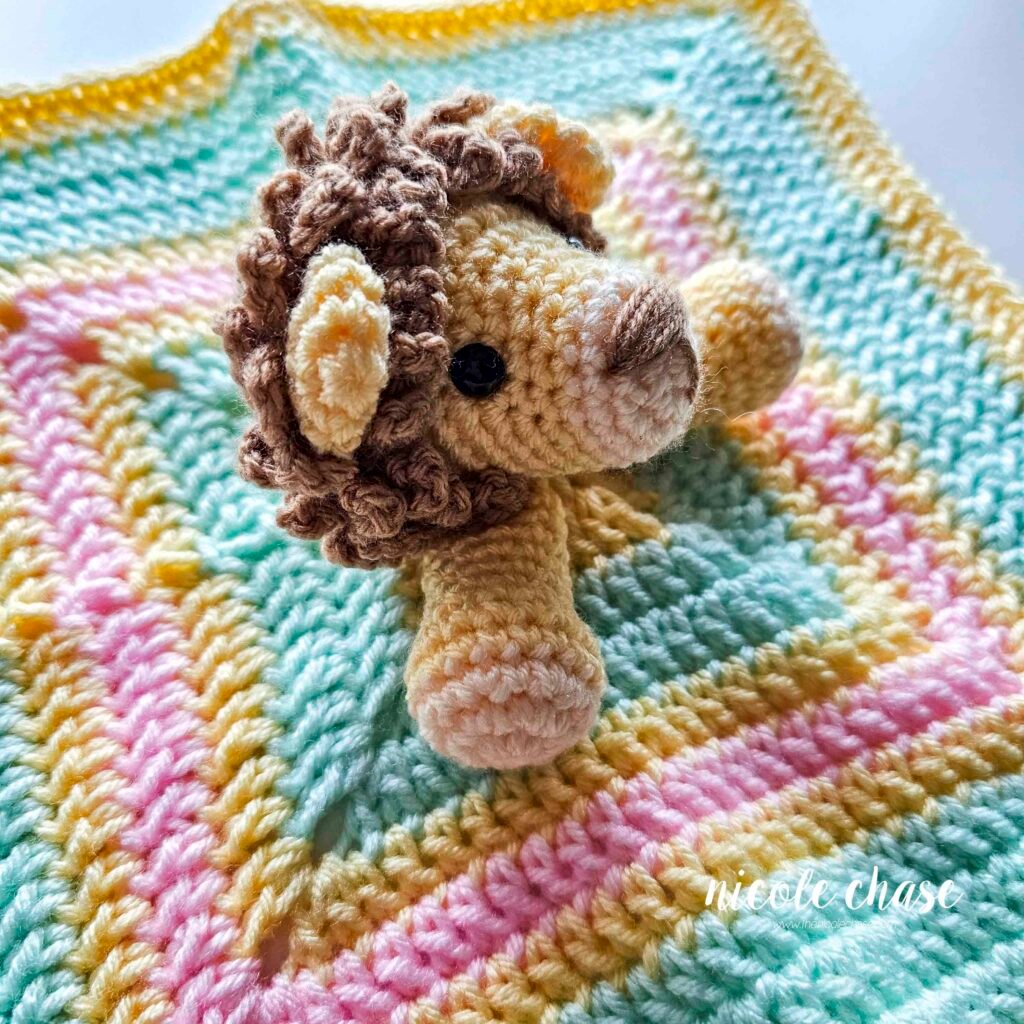 Crochet arm placement for the Hug Me Lion Lovey crochet pattern after being sewn in place, view 1.