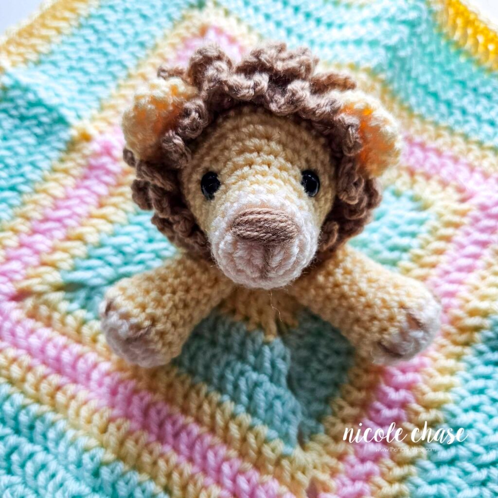 Embroidering nails on the arm of the crochet lion lovey, step 6.