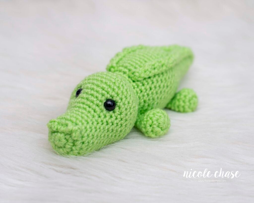 A side view of Alan, a finished green amigurumi plush from this free alligator crochet pattern, showcasing the detailed snout and textured ridges along the back.