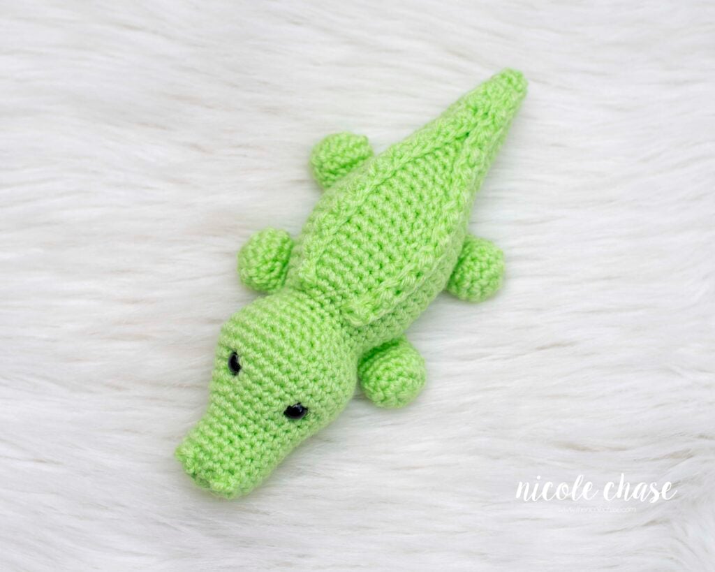 Top-down view of a green amigurumi alligator from this free alligator crochet pattern showing the symmetrical placement of the legs and the textured ridges running down the center of the crochet croc back.