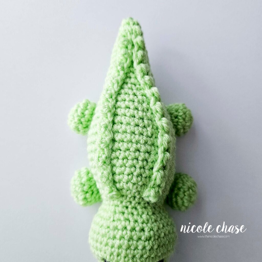 The ridges have been sewn into place on the back of the crochet alligator's body, view 2.
