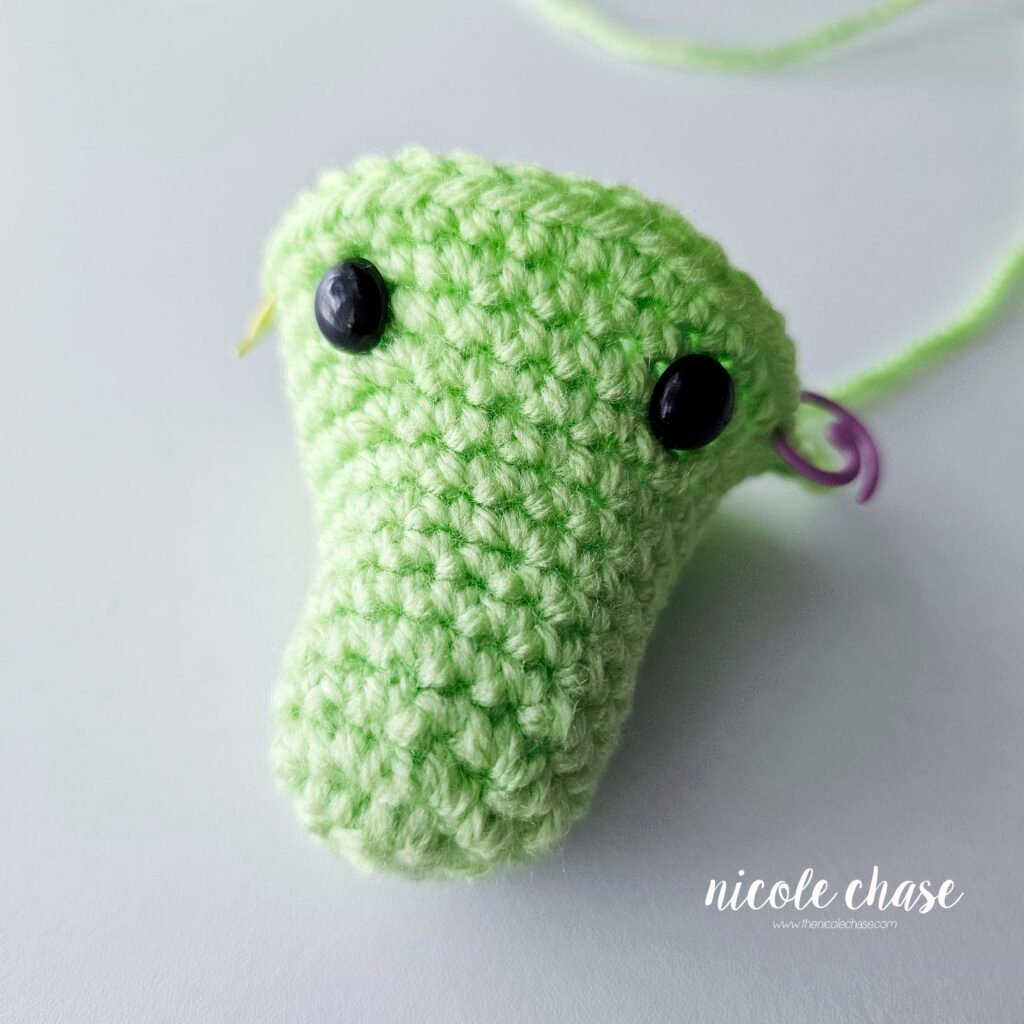 The head of the crochet alligator pattern demonstrating the placement of the safety eyes.