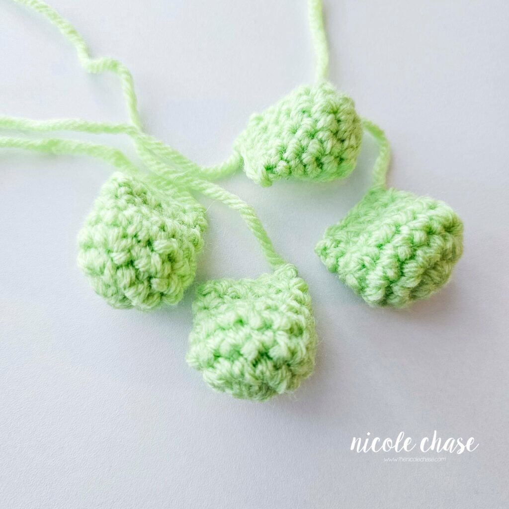 The four finished legs of the crochet crocodile pattern in a bright green yarn, waiting to be attached.