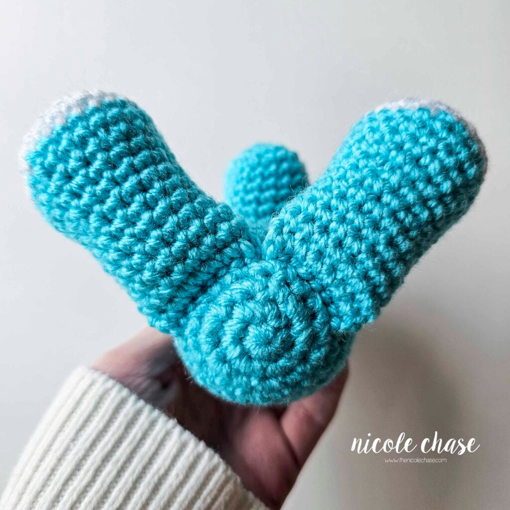 The crochet legs have been sewn into place on the bottom front of the body, view from the bottom.