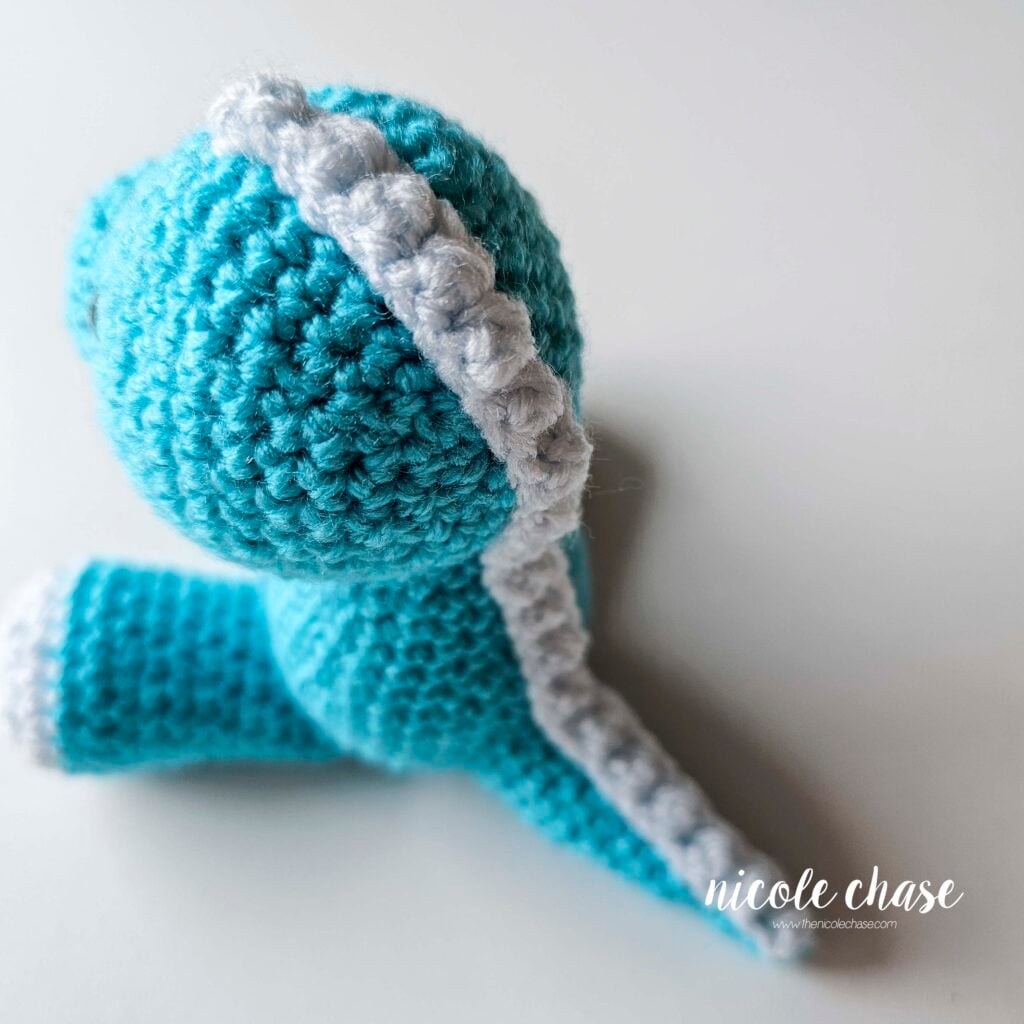 The light blue ridge has been sewn into place on the back of the body. This is a side angle, top down view of the whole ridge piece going down the head, body, and tail.