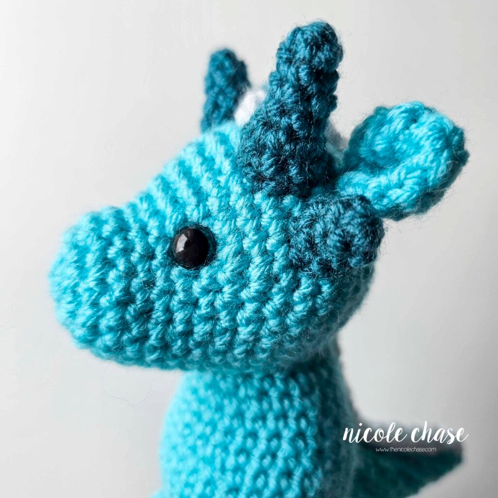 A side profile view of the dragon's head with the small spikes sewn into place just below the large spikes and in front of the ears.