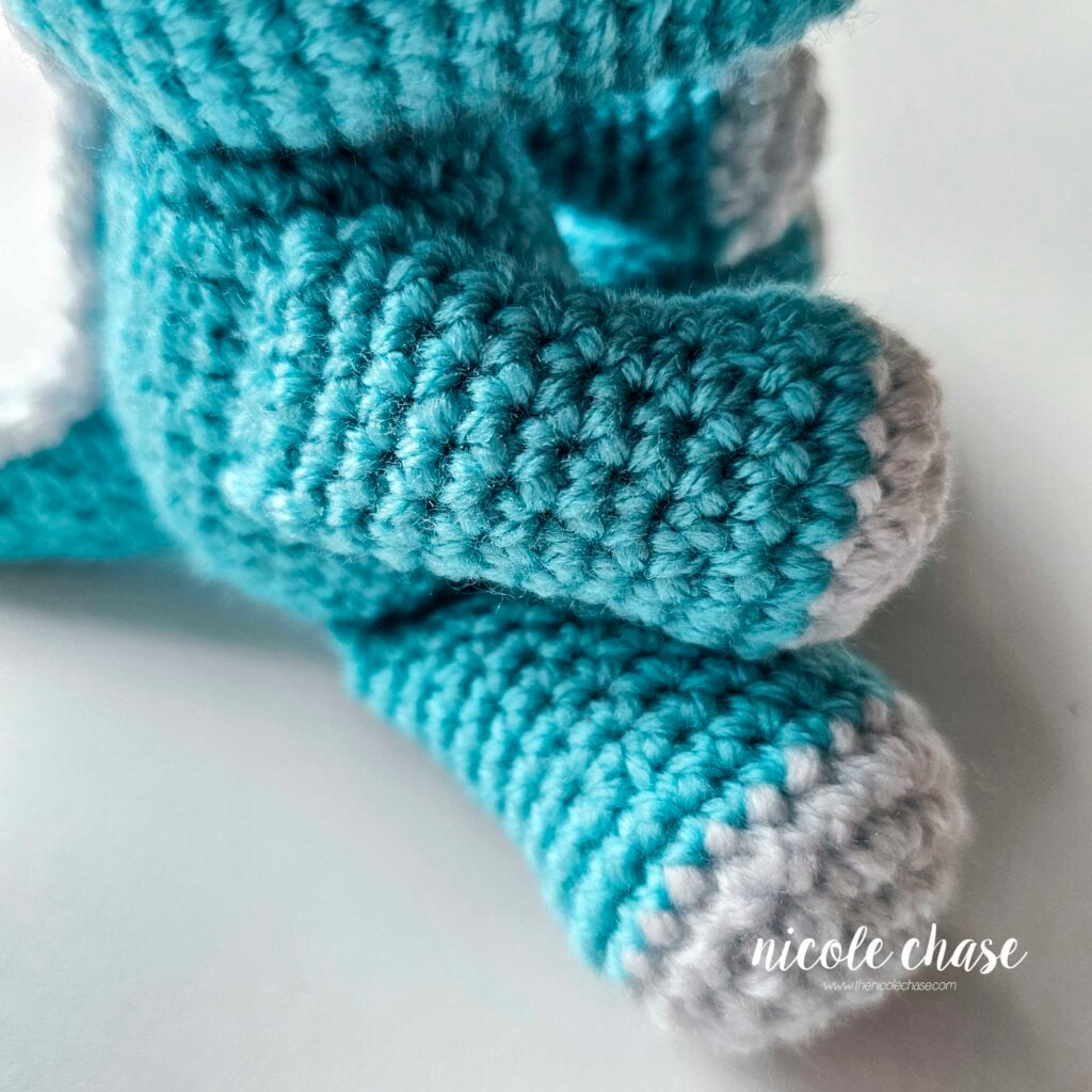 A close up of the side of where the crochet arm is sewn onto the side of the dragon's body.