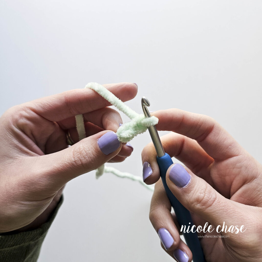 Two hands crocheting a chain 2 as the start of the magic ring alternative for use with plush, chenille, or velvet yarns. 
