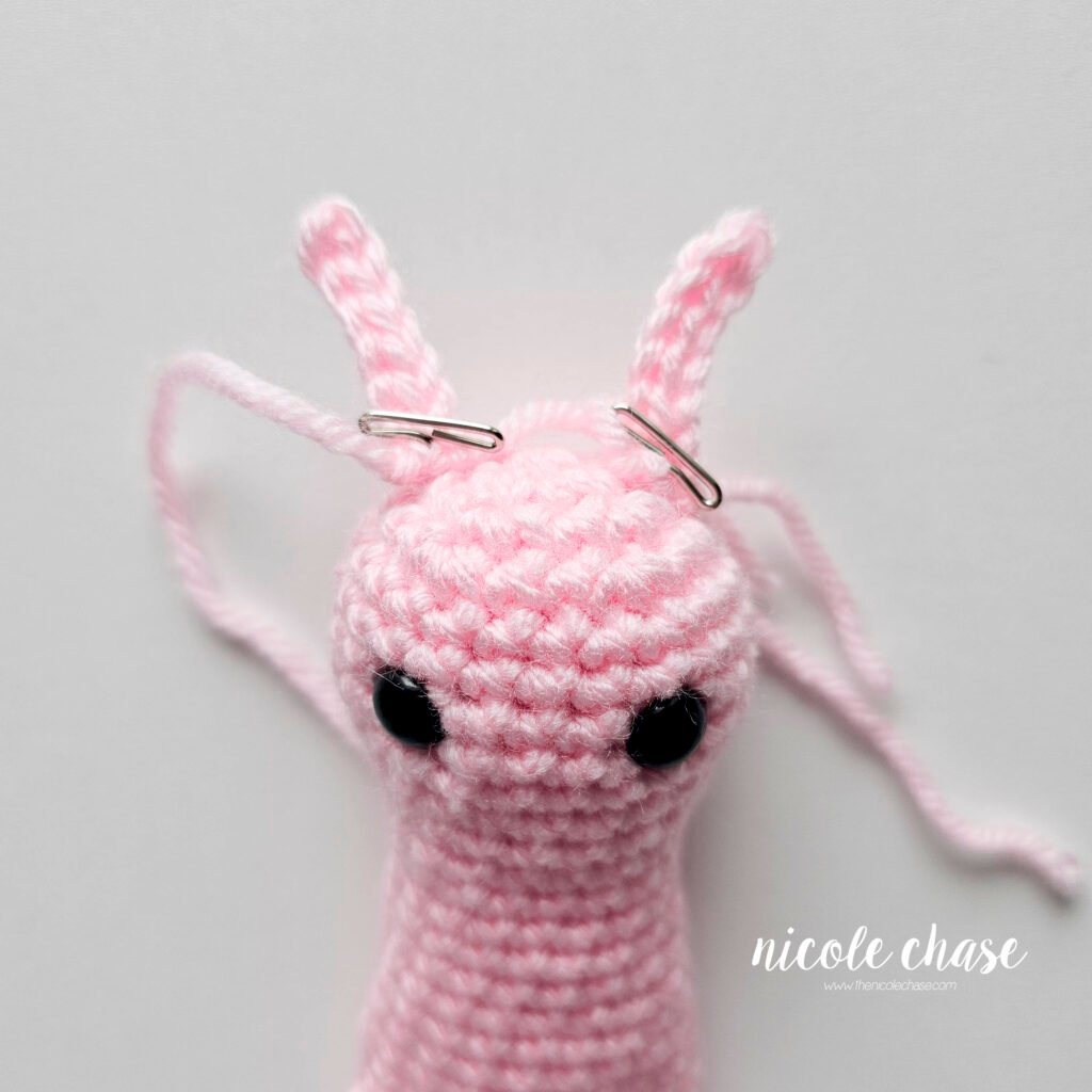 The antennas for the snail crochet pattern pinned into place on top of the head prior to sewing.