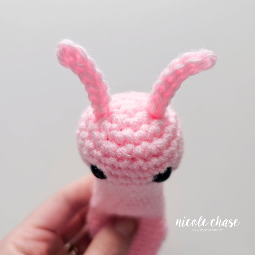 The two crochet snail antennas have been sewn into place on top of the head, view 1.