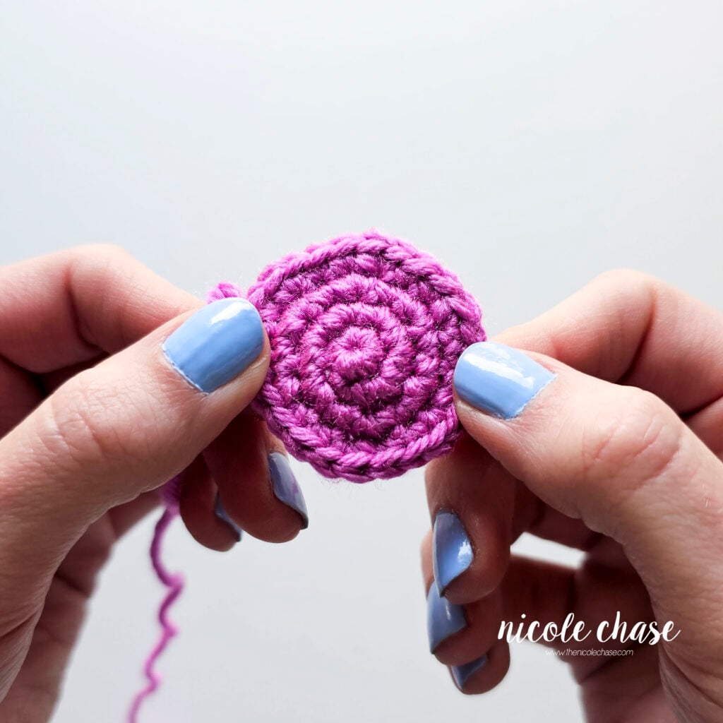 A close up of a round crochet swatch in purple yarn with tight single crochet stitches.
