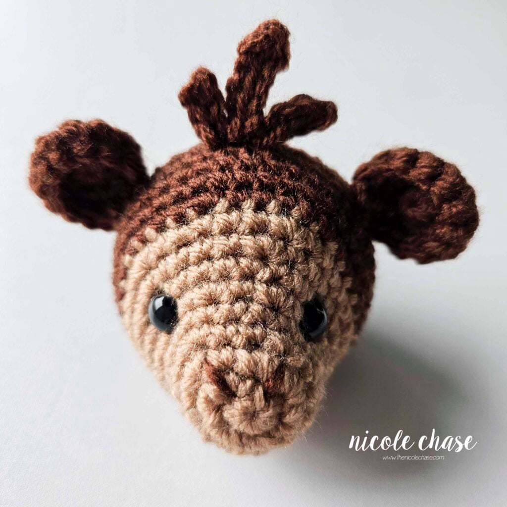 The yarn tails have been hidden inside the piece and the embroidered nostrils on the face of the crochet monkey have been completed. 