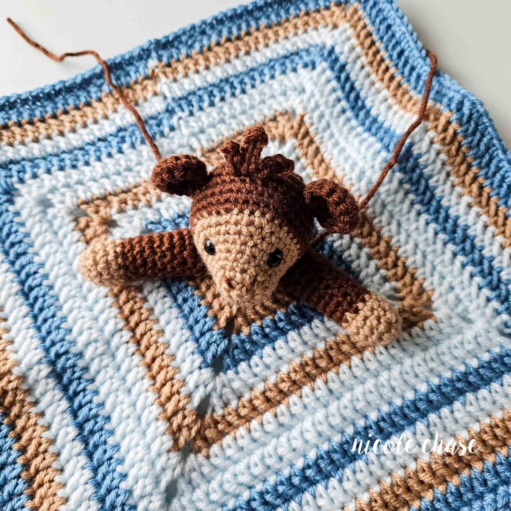 The monkey's crochet arms are placed next to the head on the center of the security blanket and are awaiting sewing. 