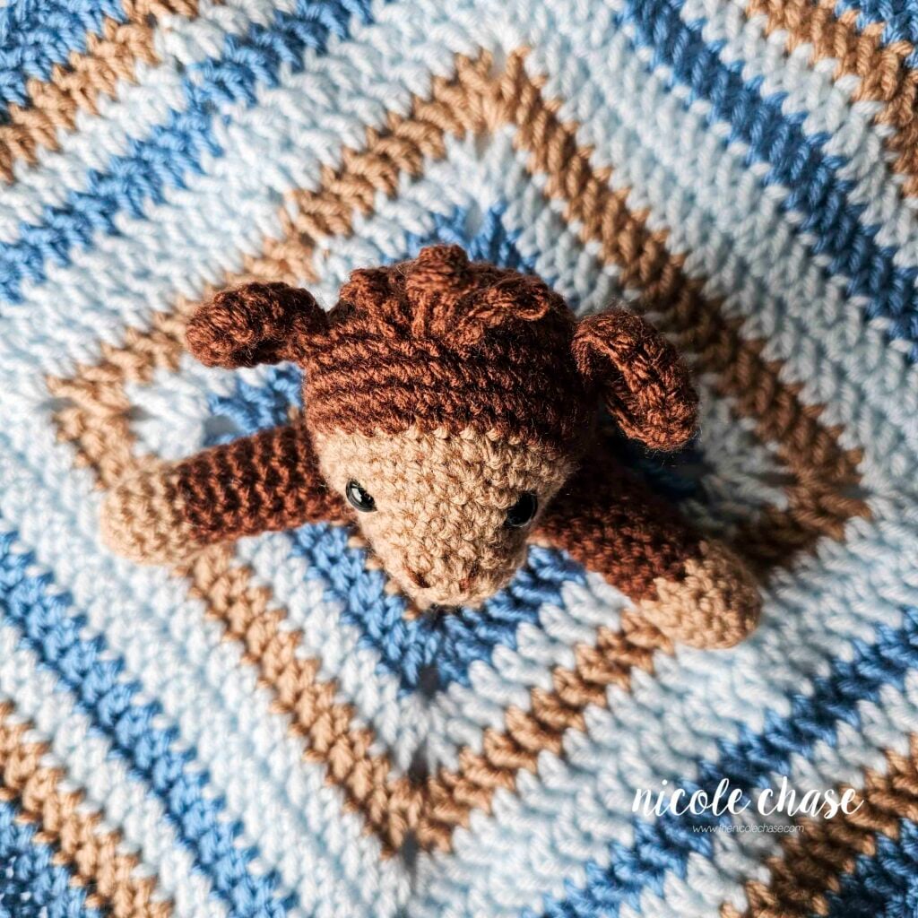 The crochet arms are sewn into place on each side of the head in the center of the security blanket. 