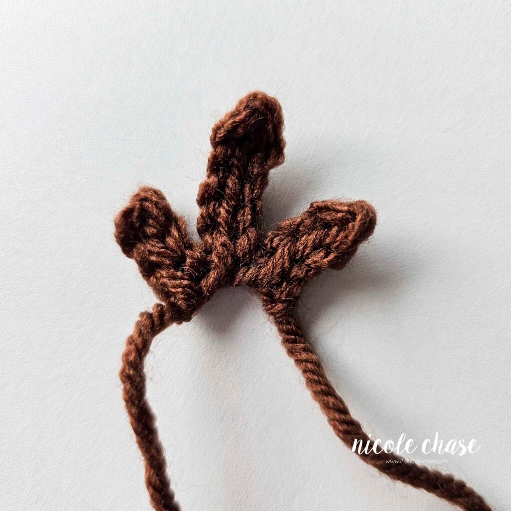 A brown tuft of hair crocheted in dark brown yarn for the monkey lovey crochet pattern. 