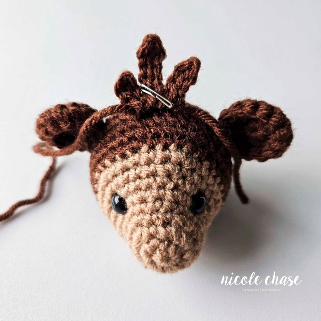 The brown hair is pinned in place on the top of the amigurumi monkey head between the two ears and is ready for sewing in place. 