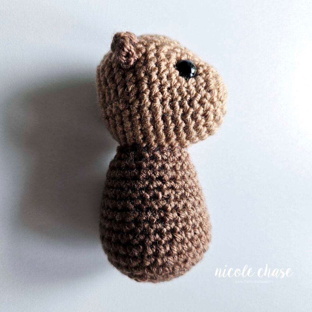 The body has been sewn into place on the bottom of the crochet head of the otter, a side view.