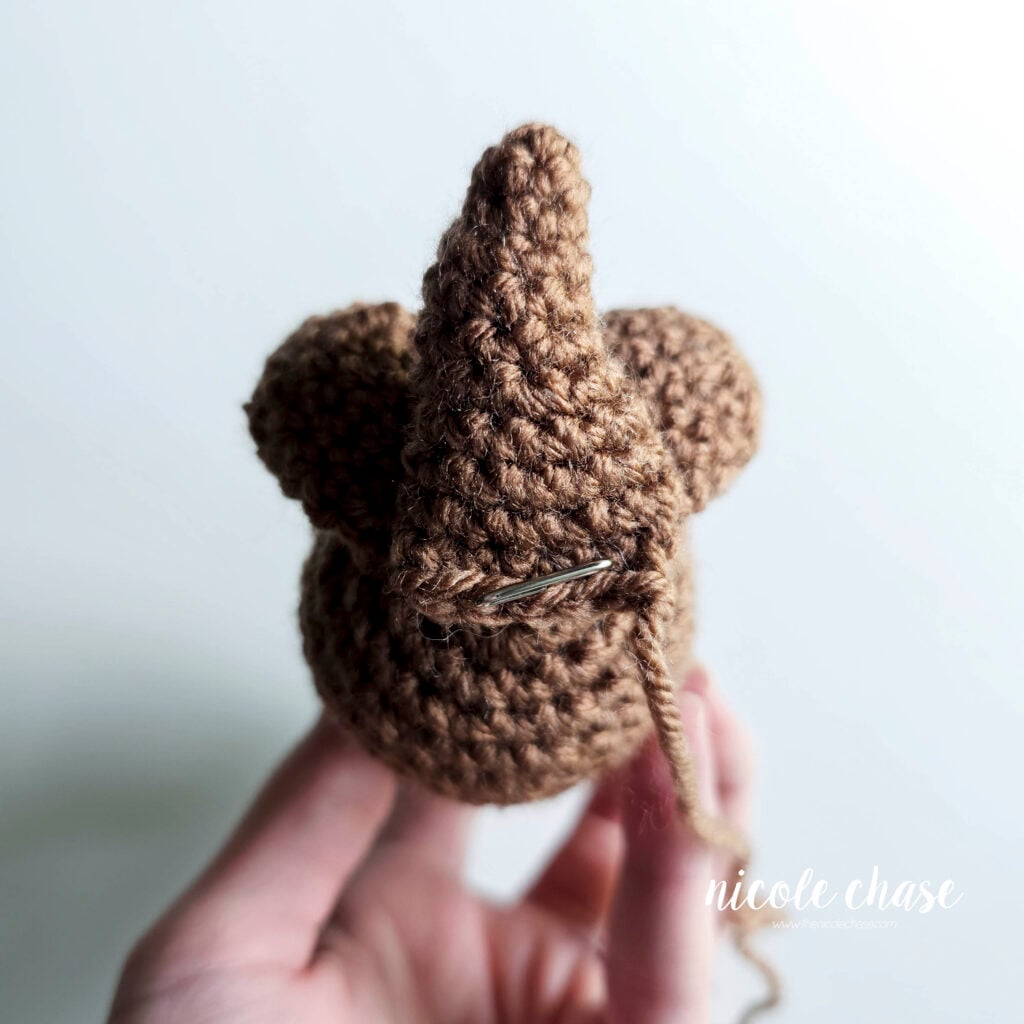 The crochet otter's tail has been pinned into place on the bottom of the body.