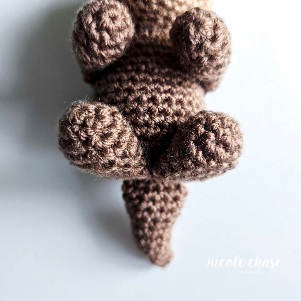 A view of the otter's crochet tail sewn into place in the bottom of the body, a view from the front.