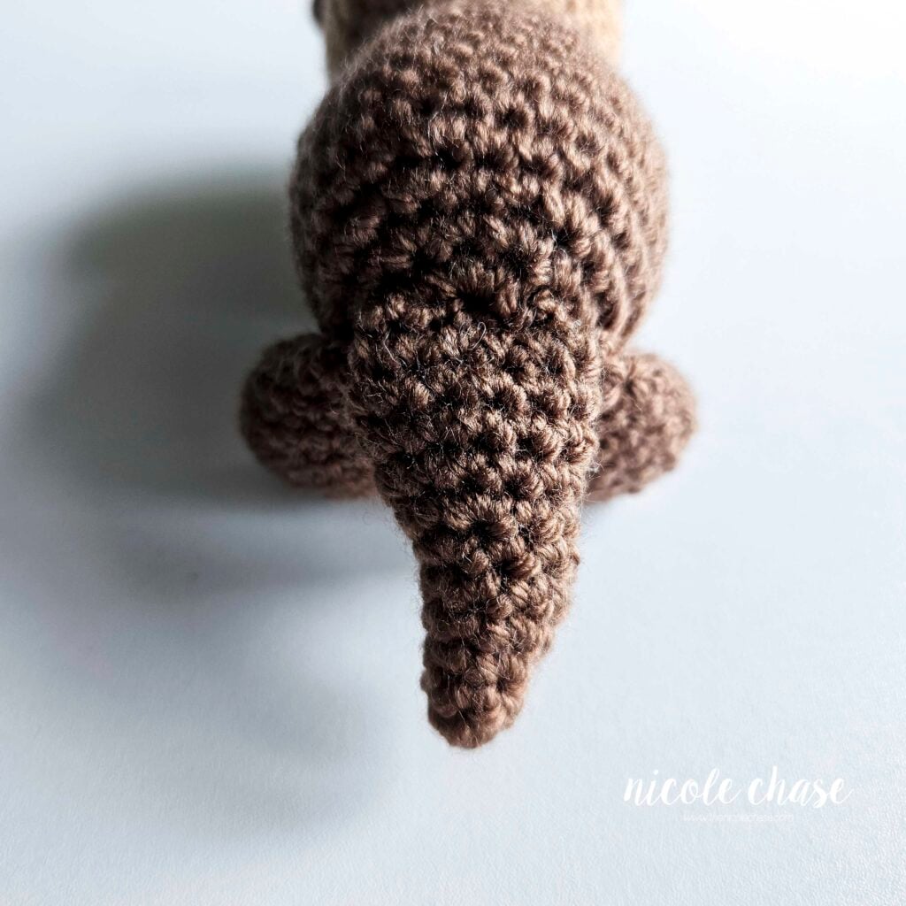 The back of the crochet otter's body after the tail has been sewn into place.