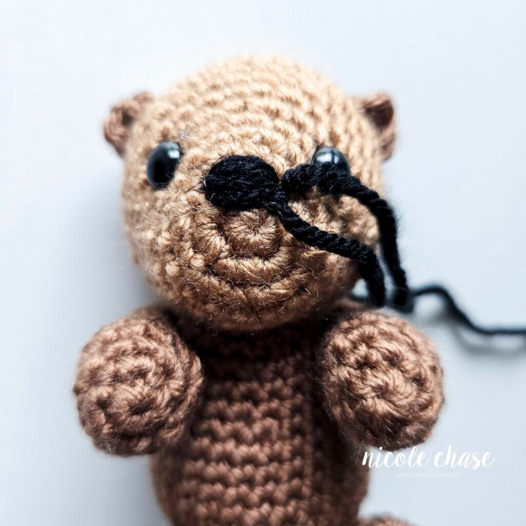 The embroidered black nose has been finished on the front of the otter's face and the ends are awaiting finishing.