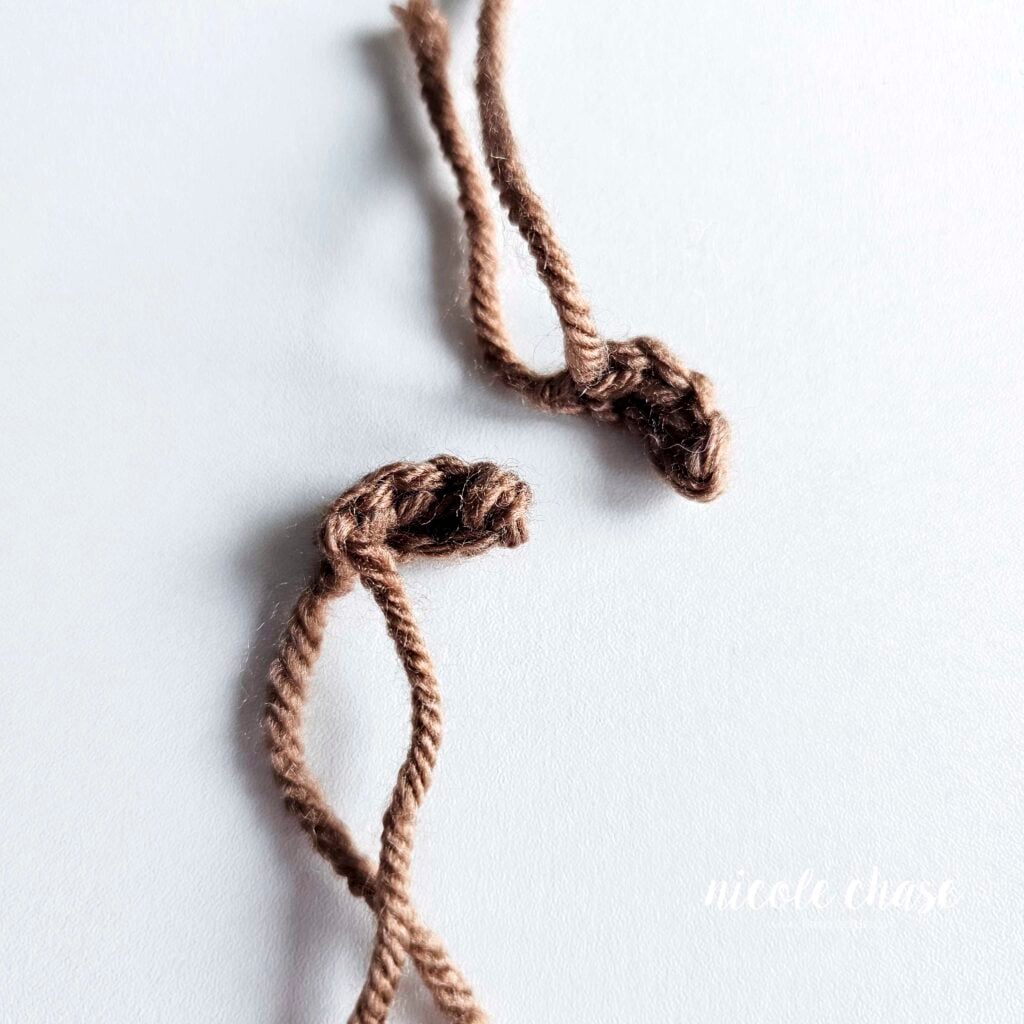 Two small crochet ears for the otter, shown in brown yarn, awaiting assembly.