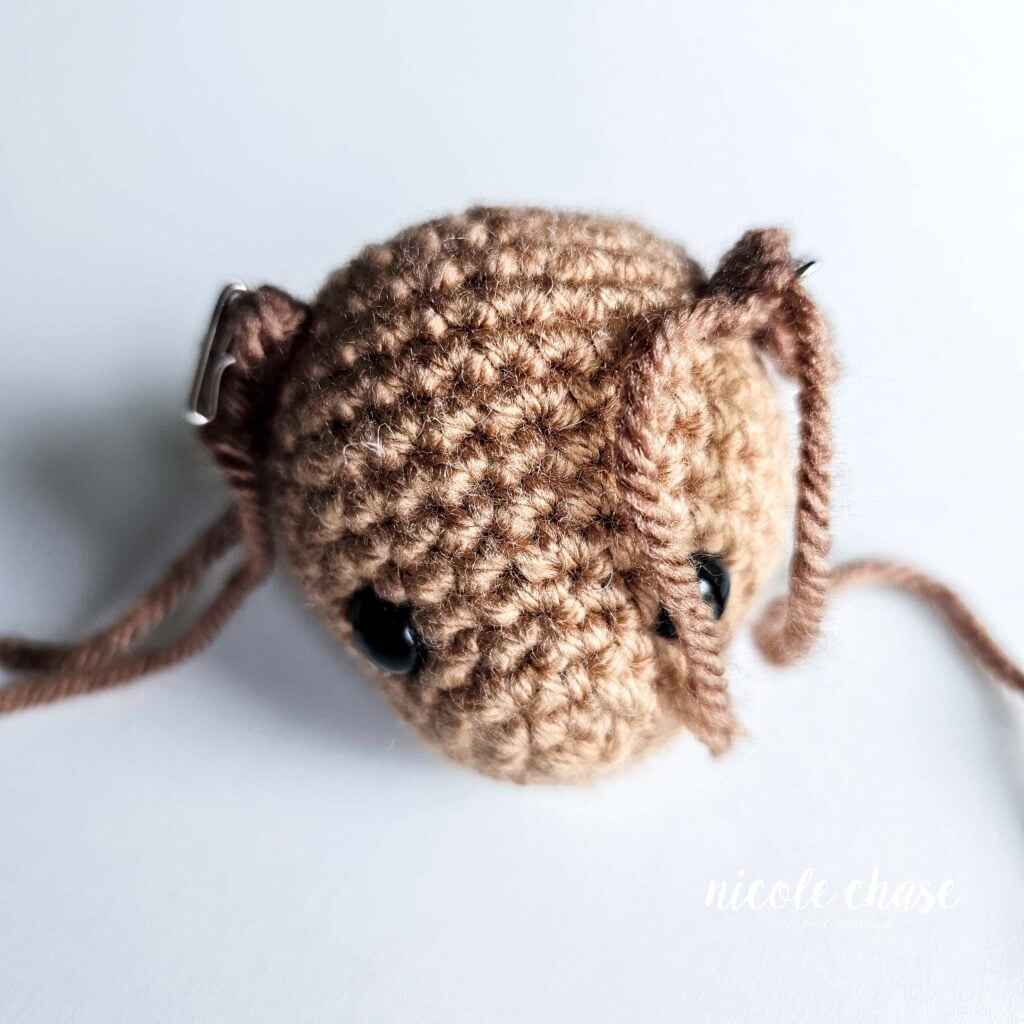 The two crochet ears for the otter have been pinned into place on each side of the head and are ready to be sewn in place.