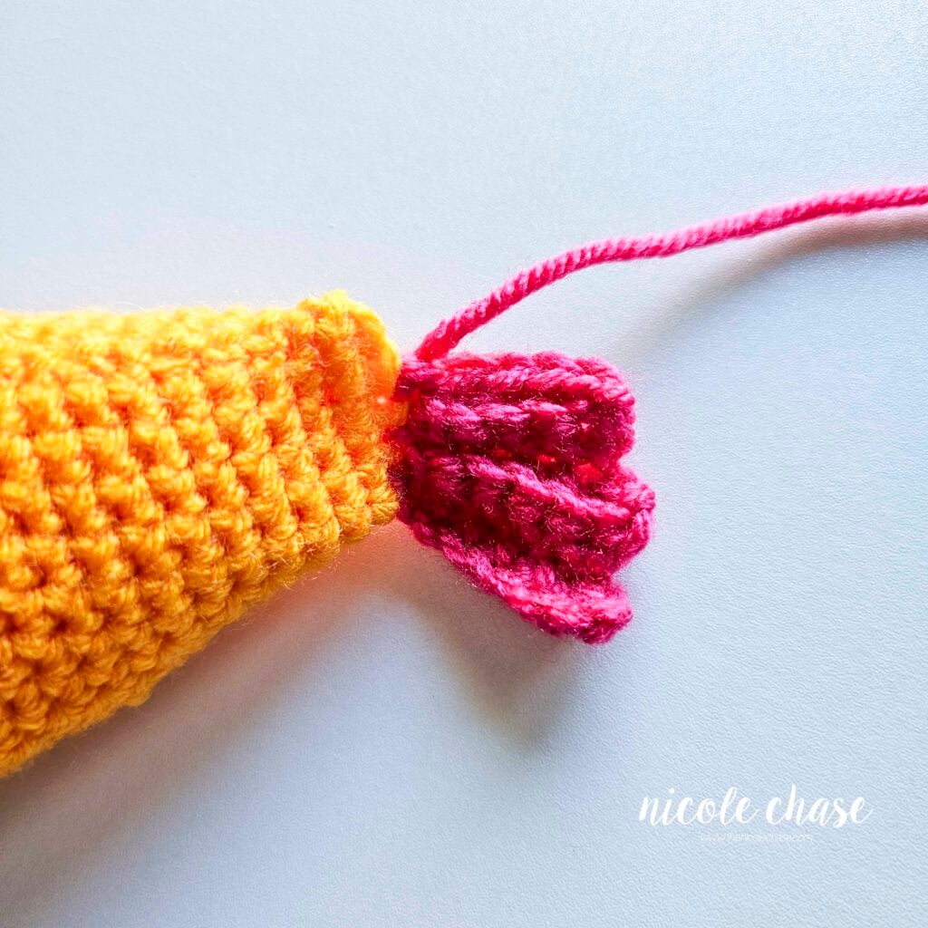 The bottom tail fin piece has been completed in pink yarn of the free fish crochet pattern.