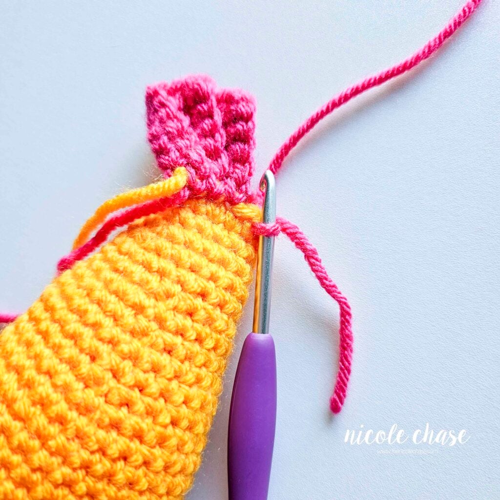Attaching the pink yarn to the top of the last round of the fish's body to start the next tail fin.