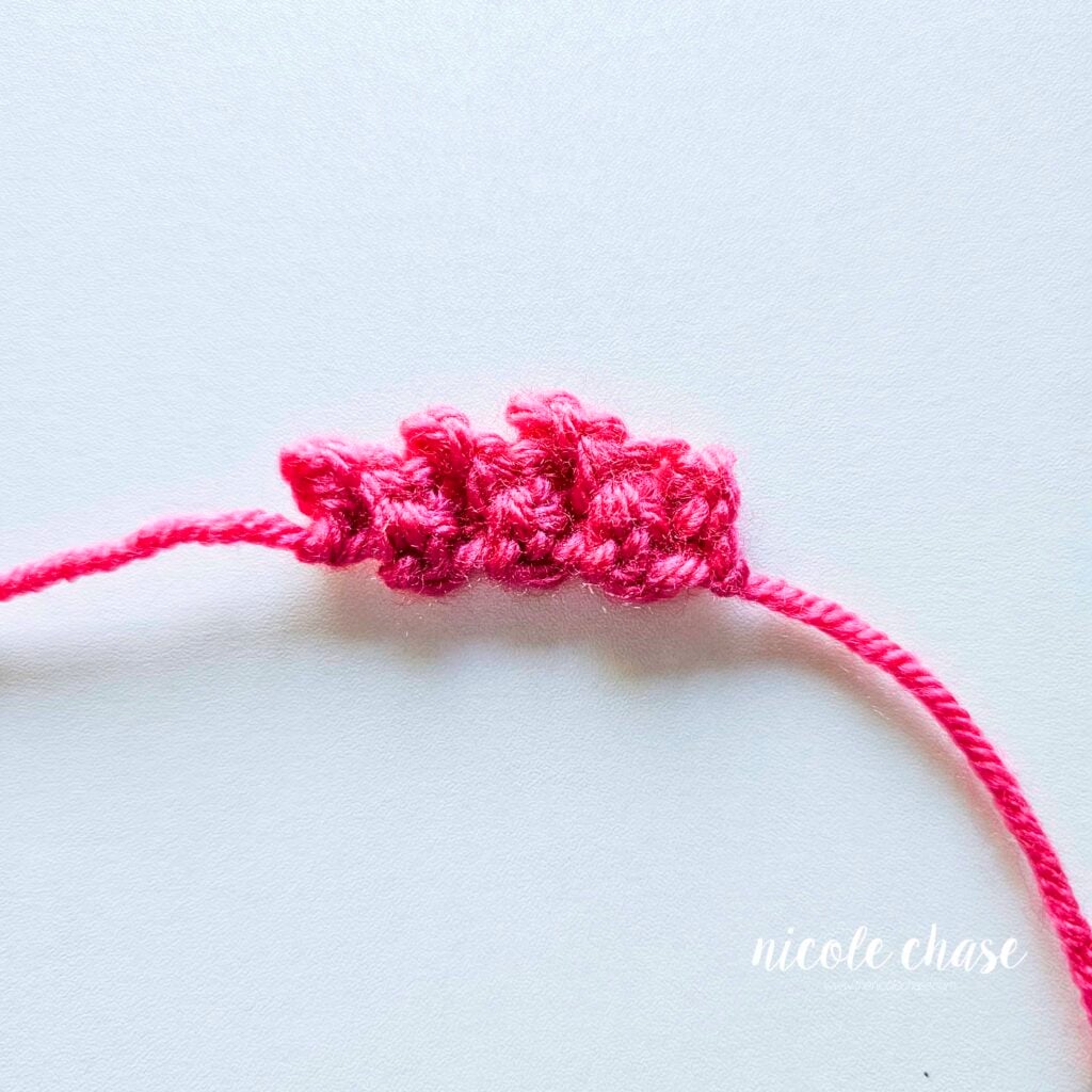 The completed top fin of the amigurumi fish made in bright pink yarn.