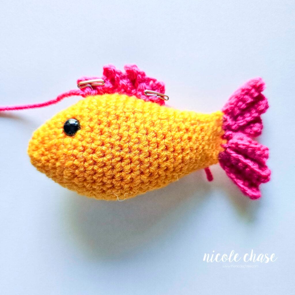 The top fin has been pinned into place on top of the crochet fish and is awaiting sewing.