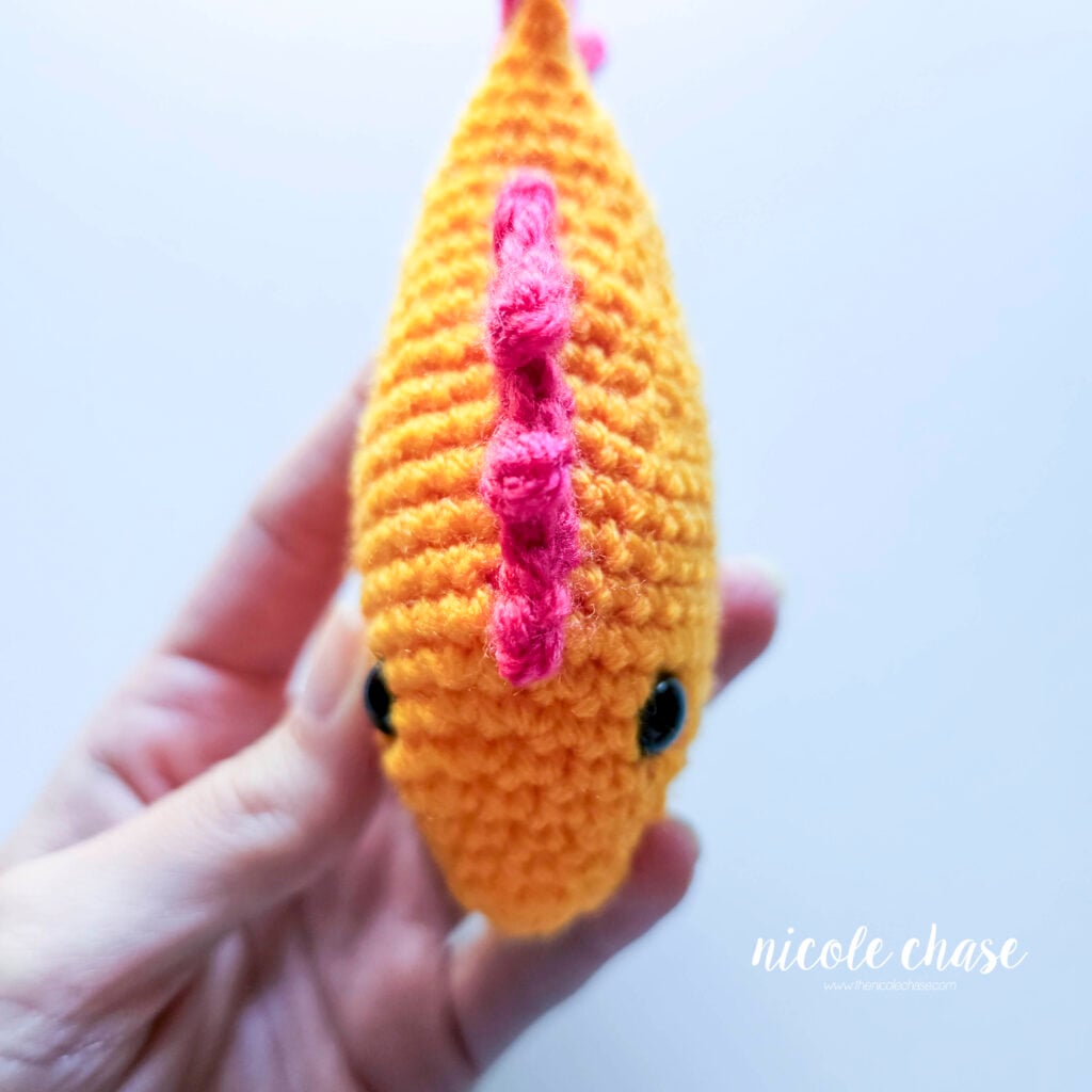 The top fin has been sewn into place on the top of the crochet fish, a view from the top.