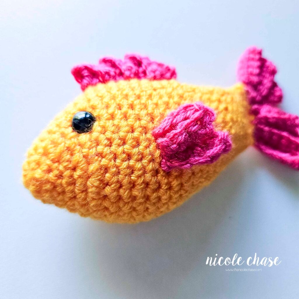 The side fin has been sewn into place on the side of the amigurumi fish, a side angled view of the fish.