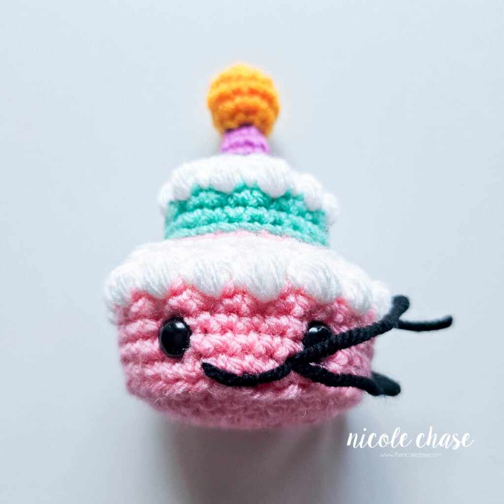 The smile has been completed and the yarn tails remain on the side of the mouth.