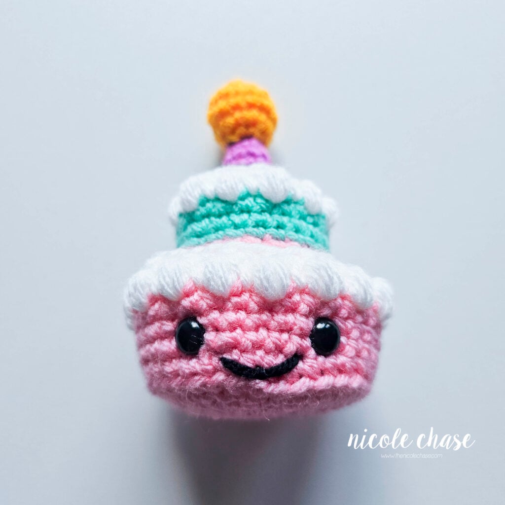 The yarn tails have been secured and hidden inside the piece, completing the birthday cake's embroidered smile.