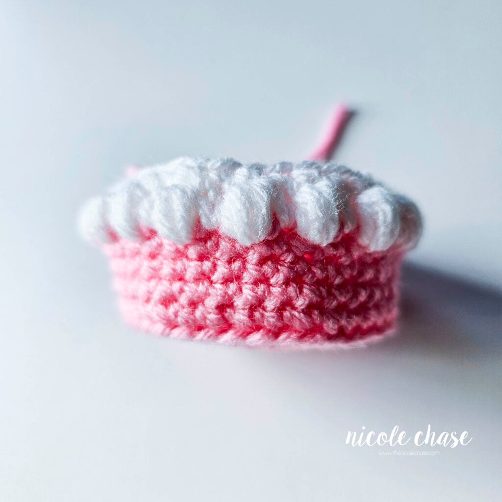 The first tier of the birthday cake amigurumi before inserting the safety eyes.