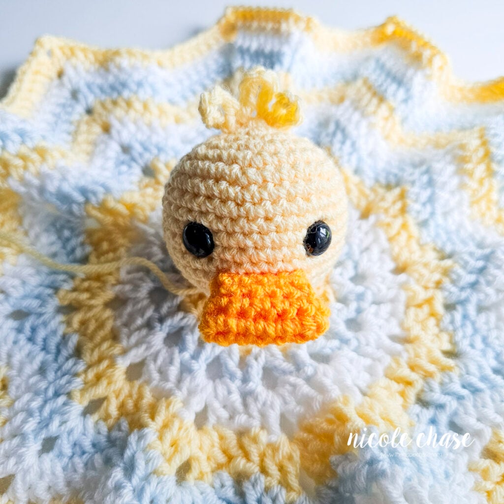 Crocheted duck head pinned centrally to the middle of the star lovey blanket before sewing.