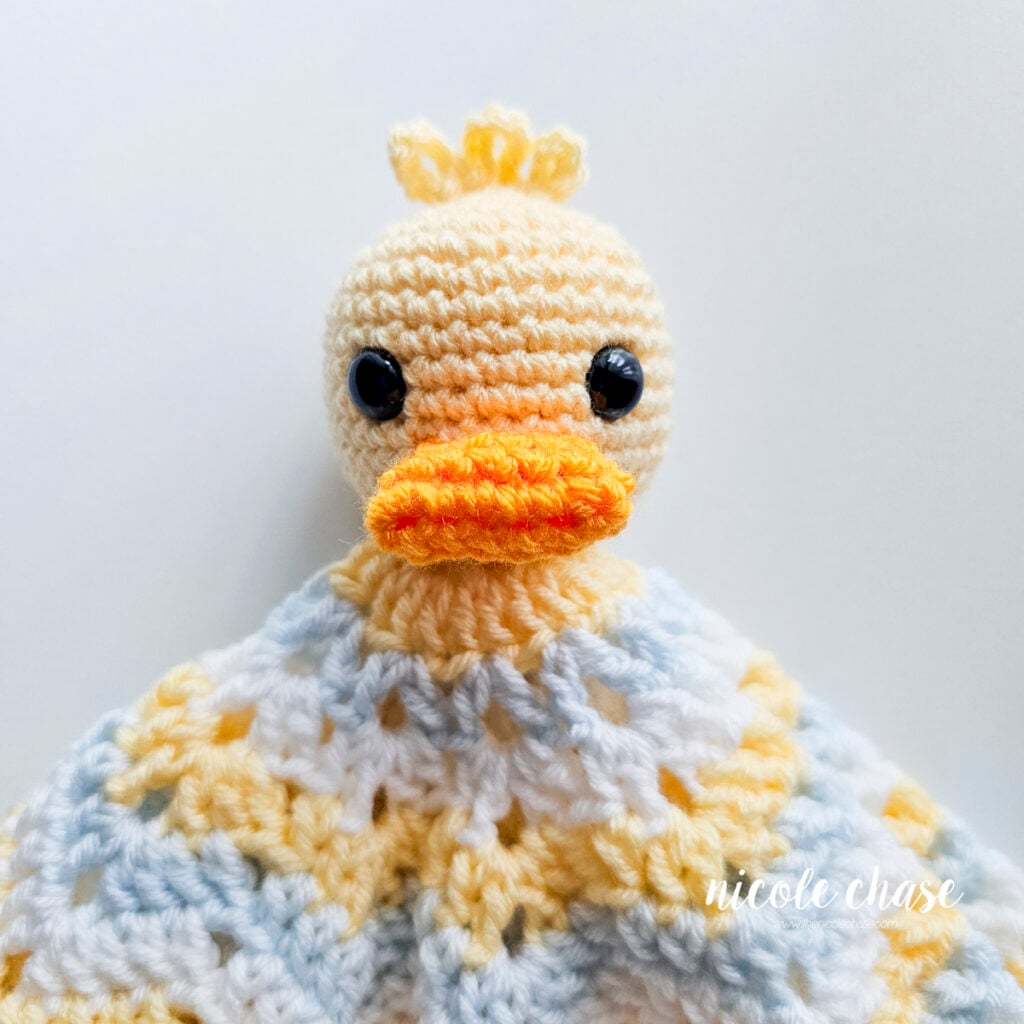Front-facing view of the crocheted duck head fully attached to the star blanket base.