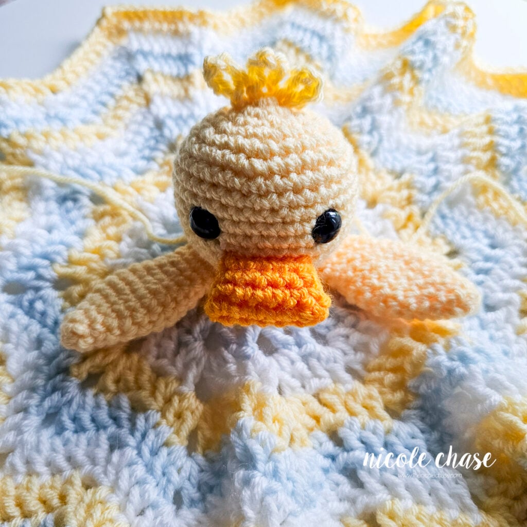 Crocheted duck wings pinned to the base of the head on the lovey blanket before sewing.