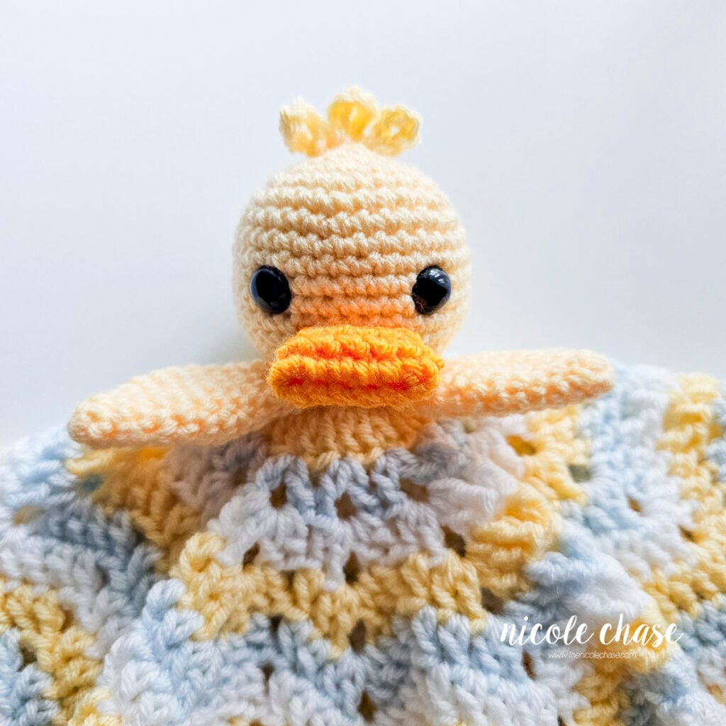 Front view showing both yellow wings securely stitched beneath the duck's head onto the blanket.