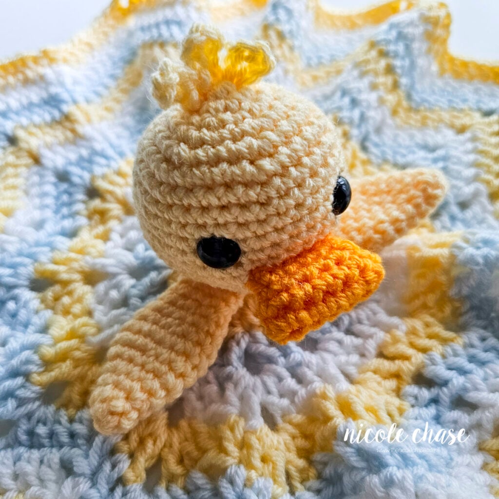 Top-down angled view of the completed crochet duck lovey with head and wings fully assembled.