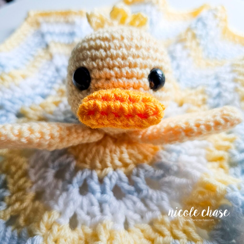 Close-up shot of the duck head with wings attached, reaching out over the star blanket.