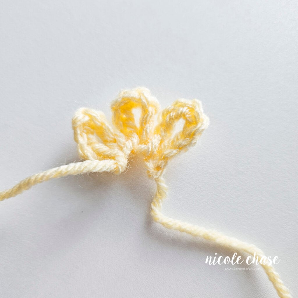 Small yellow crocheted tuft of feathers with three looped petals to sew on top of the duck's head.