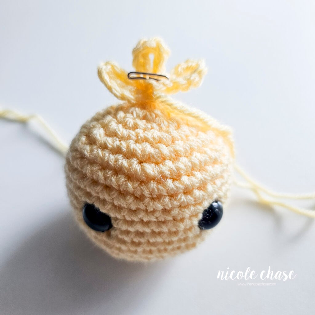 Crocheted duck feather tuft pinned to the top of the stuffed head before sewing.