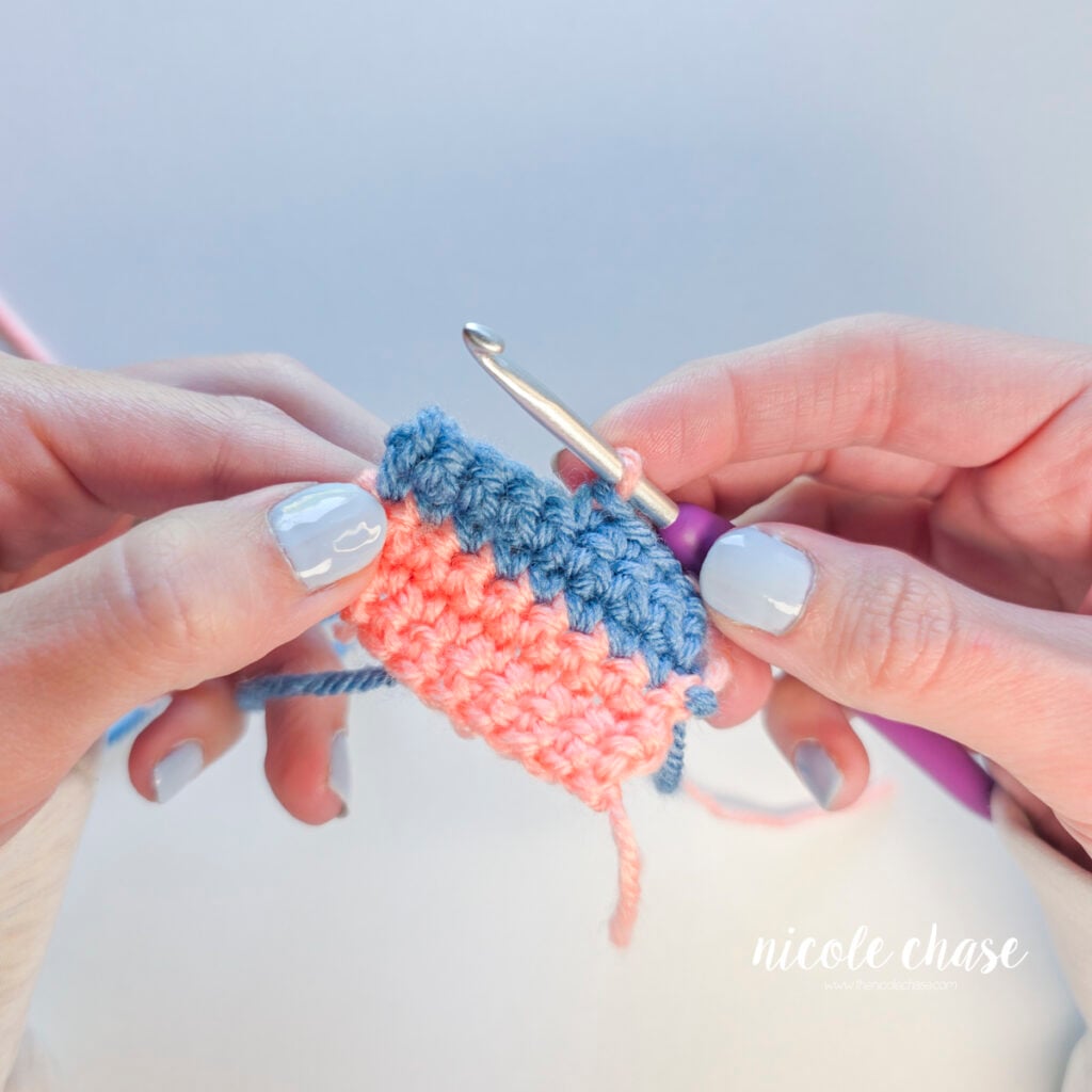 A single pink loop remains on the crochet hook after completing the color change.
