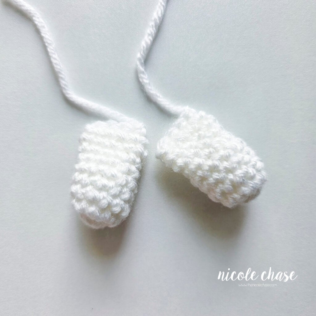 Two finished arms for the Gilbert the Ghost amigurumi pattern, made in white yarn.