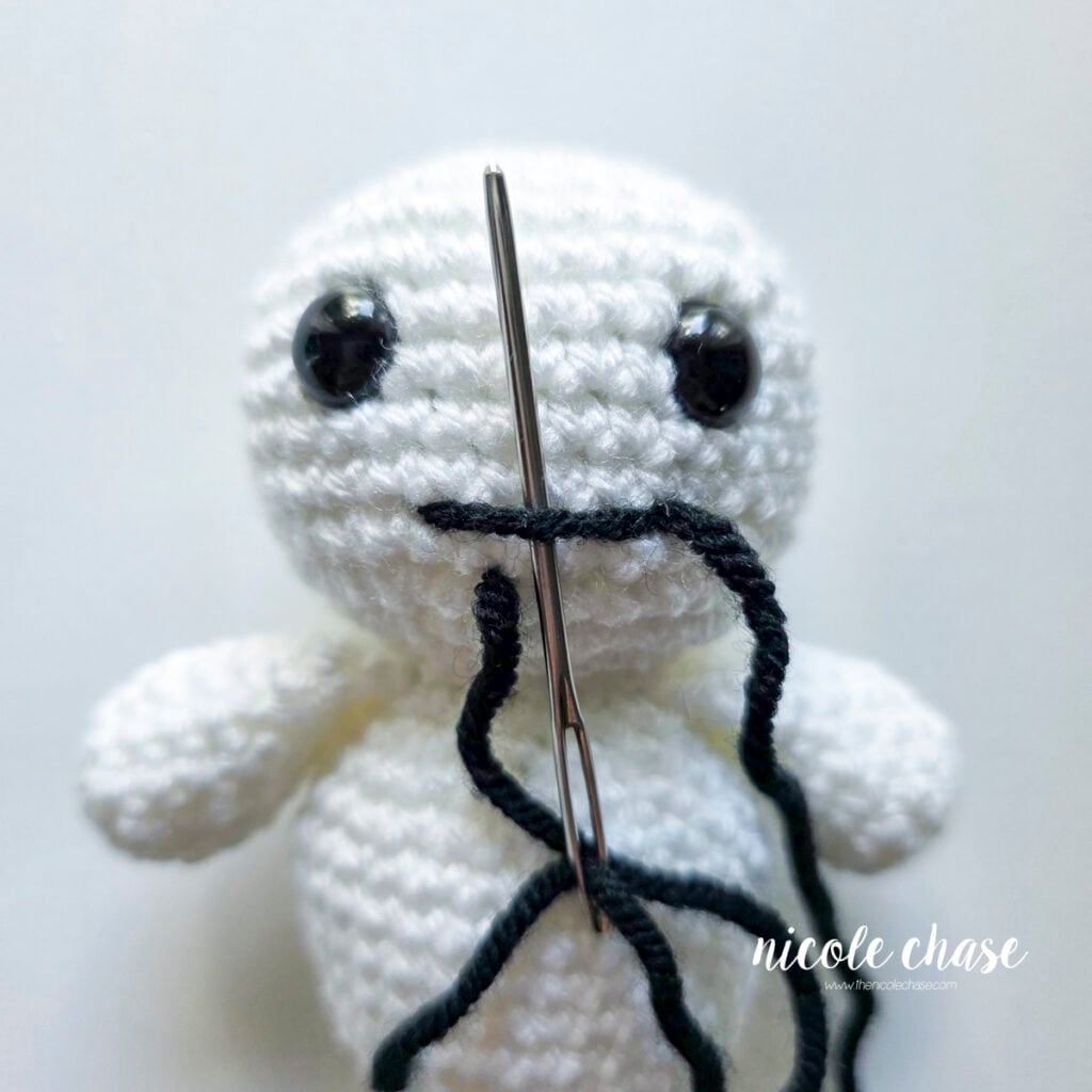 A straight line has been formed across the ghost head and the yarn needle is inserted under the line.