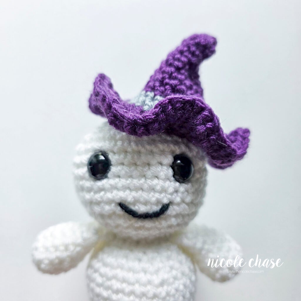 The purple witch hat has been attached to the top of the crochet ghost's head at an angle.