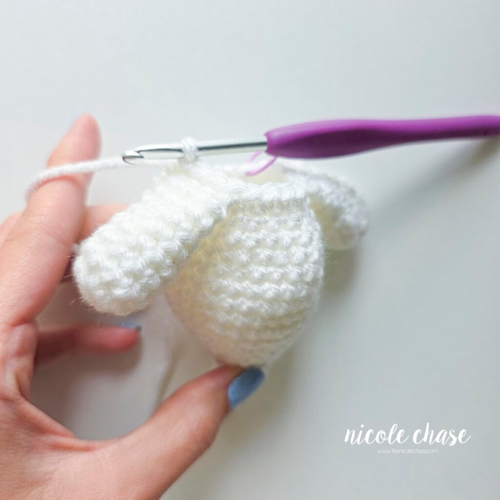The second arm has been crocheted into place on the body of the ghost amigurumi.